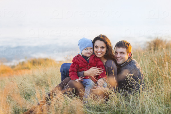 Portrait of the little girl with a funny hat and father and mother smiling outdoors. Family leisure outdoors concept