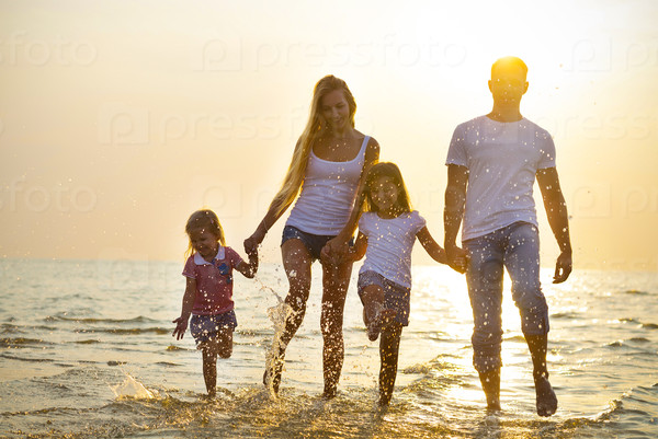 Happy young family having fun running on beach at sunset. Toned photo. Family traveling concept. No effects - real sun