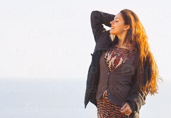 Portrait of the beautiful brunette woman at the windy autumn day relaxing on coast feeling good