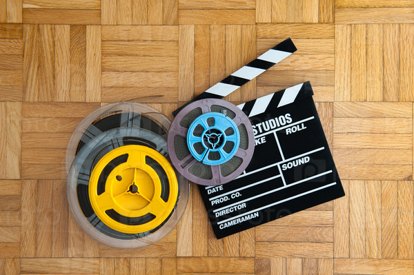 Movie clapper board cinema and super 8 coloured film reels horizontal frame on wooden floor