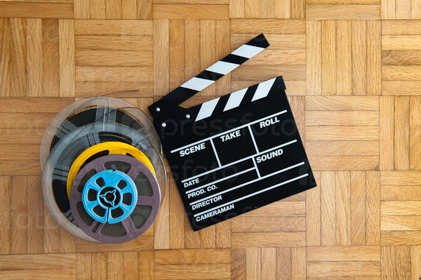 Movie clapper board cinema and super 8 coloured film reels horizontal frame on wooden floor