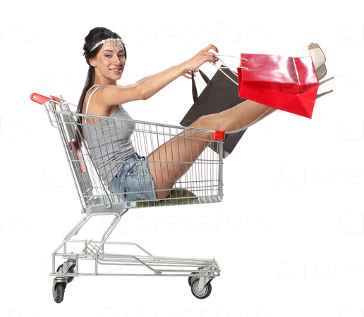 Pretty brunette woman sits in an empty shopping trolley with a shopping bags, isolated on white background, stock photo