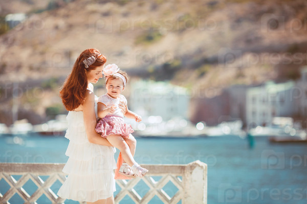 Happy woman with daughter resting at beach in summer outdoor