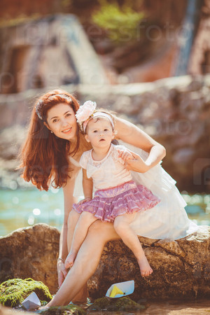 Portrait of a Happy family of woman and child having fun by the blue sea in summertime