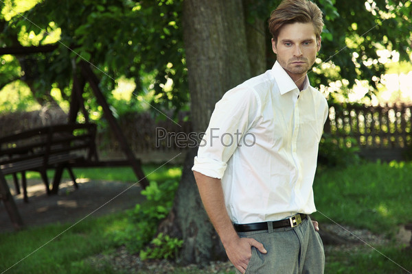 Portrait of young beautiful courageous man against summer garden