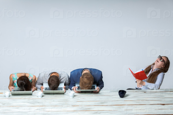Business team working on their business project together at office on light gray background. all buried his head in the computer screen. boss laughing. copyspace image.