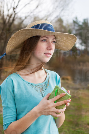 Freckled girl in hat standing with note and looking away in windy weather