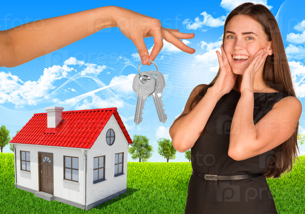 Happy young lady with house and hand holding keys, stock photo