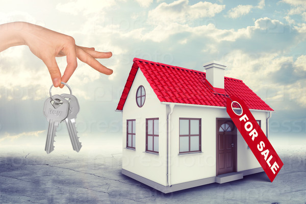 House for sale with hand holding keys on blue sky background