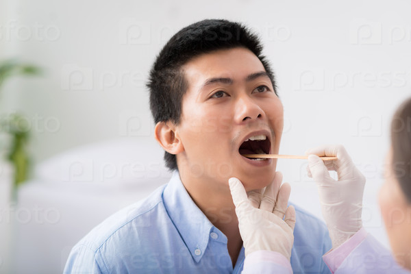 Doctor examining throat of patient