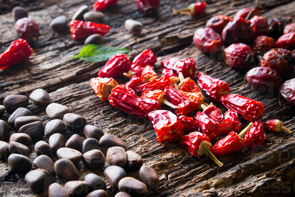 leaf, pine nuts, dried red peppers and wild rose on wooden background close-up