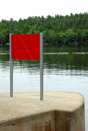 Red sign on waterfront in front of forest