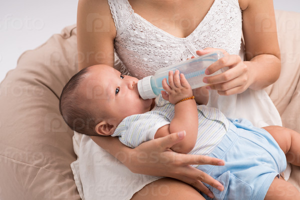 Cropped image of mother feeding one month son from the milk bottle