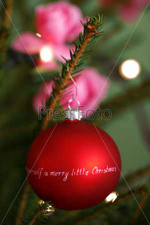 Christmas decorations: bright red ball with wish written on it on a christmas tree