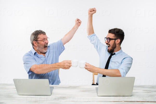 The two colleagues working together at office on white  background. both happy men are getting good news. concept of  success in business. they rejoicing and clinking cups