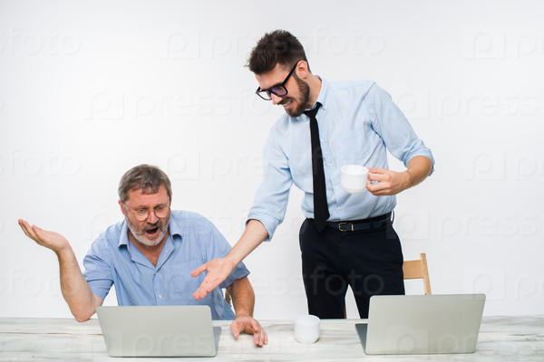 The two colleagues working together at office on white background. The old man getting bad news. the young man is happy. concept of competition in business and jealousy, stock photo