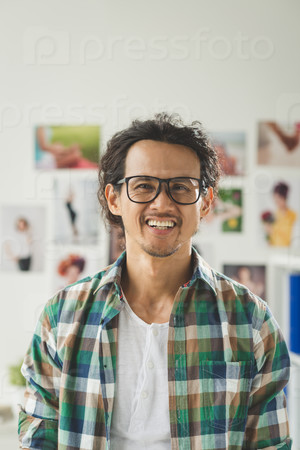 Cheerful creative young man in check shirt and glasses looking at the camera