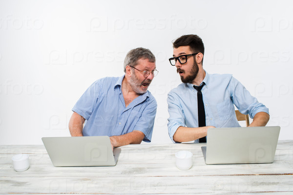The two colleagues working together at office on white  background. both are looking at the adjacent computer screen.  concept of competition in business and jealousy