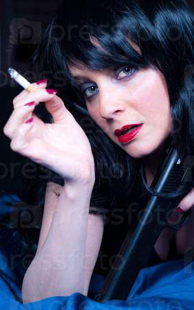 Beautiful brunette girl with cigarette and gun