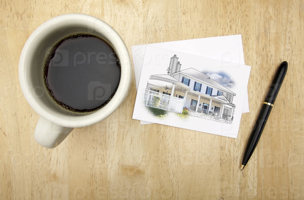 Note Card with House Drawing, Pen and Coffee Cup on Wood Background.
