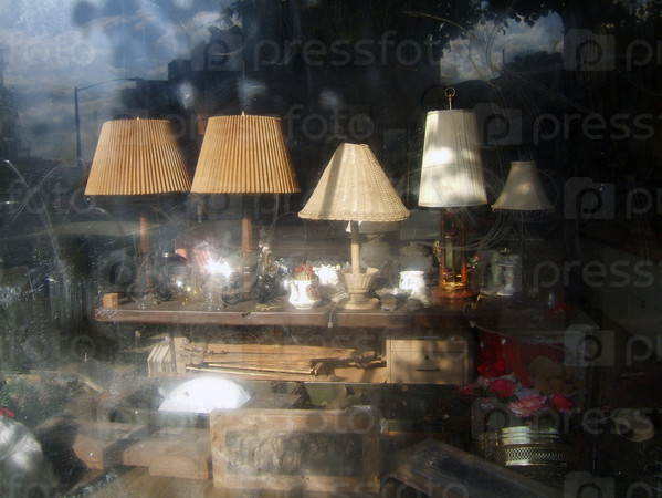 Lamps and other clutter in a dirty antique shop window