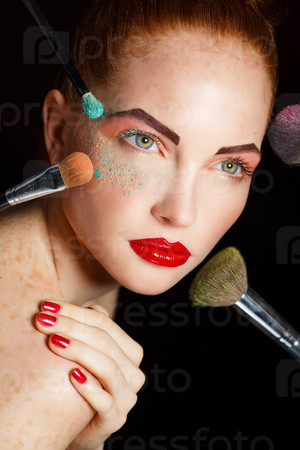 Beautiful woman  with Makeup Brushes. Bright Holiday Make-up for Brunette Woman with Brown Eyes. Orange and Yellow Make up. Beautiful Face. Makeover. Perfect Skin. Applying Makeup