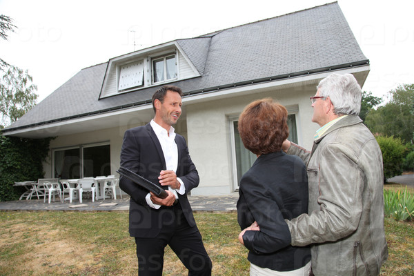 Real-estate agent with senior couple buying new house, stock photo