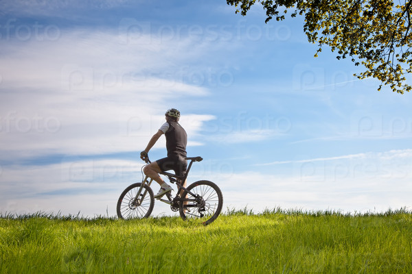 Young man takes a break in a field while mountain biking