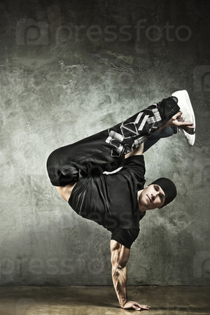 Young strong man break dance. On wall background.