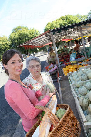 Молодая женщина, помогая пожилой женщины с продуктовых магазинов