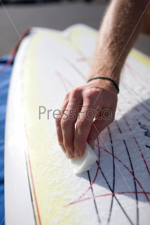man waxing his surfboard.