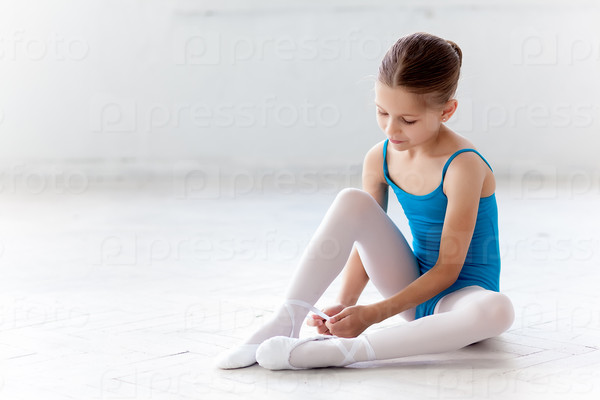 Красивая маленькая балерина в синем костюме для танцев, надевает пуанты