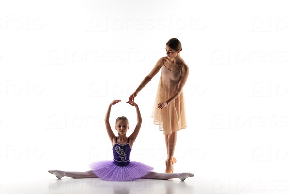 The silhouettes of little ballerina and personal classic ballet teacher in dance studio dancing on a white background