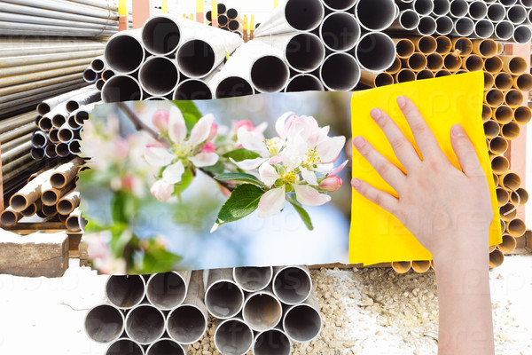 ecology concept - hand deletes industrial landscape by yellow cloth from image and spring white blossoms are appearing