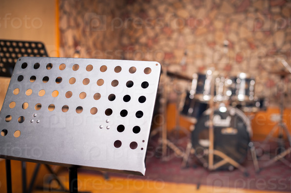 Empty music stand in studio with out of focus drums in background