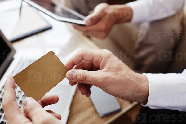Male employee holding credit card over workplace