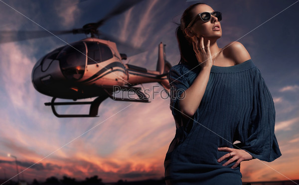 fashionable lady wearing sunglasses with helicopter in the background