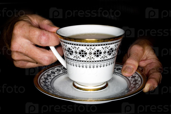 Elderly hands holding a cup of tea.