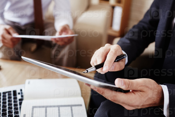 Businessman with pen pointing at screen of digital tablet