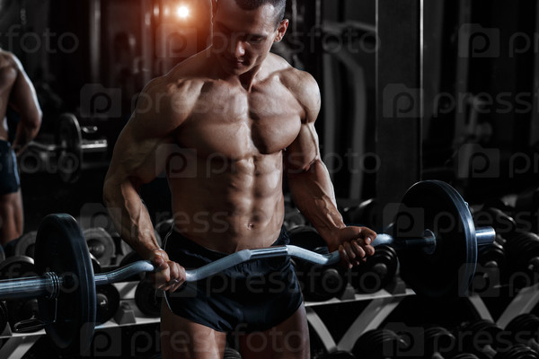 Athlete muscular bodybuilder training biceps curl with dumbbell in the gym