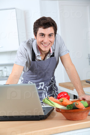Man in kitchen looking at recipe on internet
