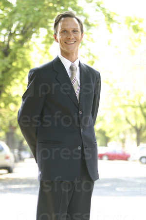 A happy man in a suit standing on the street.
