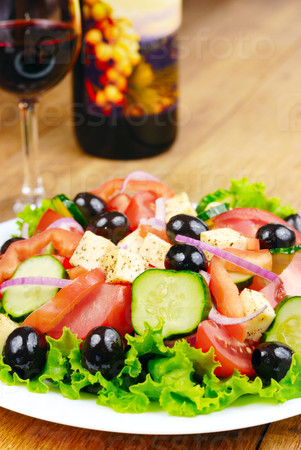 Greek salad and glass of red wine on the kitchen table
