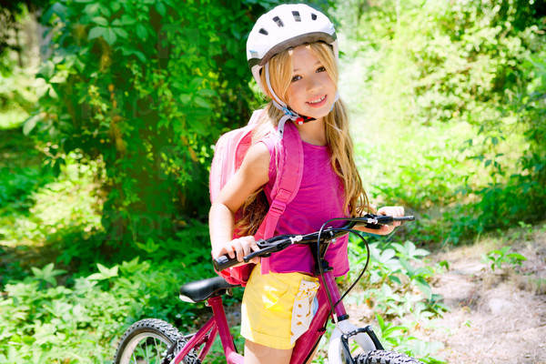 Children girl riding bicycle outdoor in forest smiling