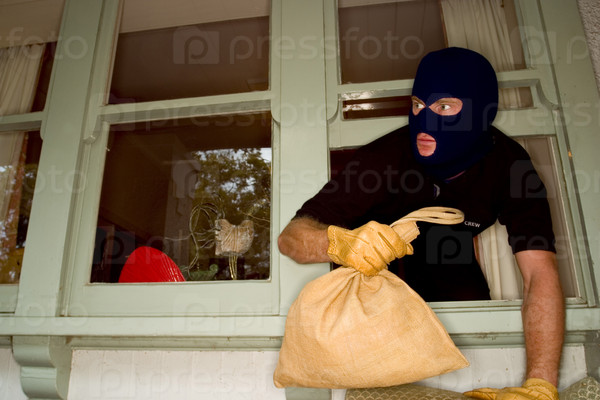 A burglar robbing a house wearing a balaclava.