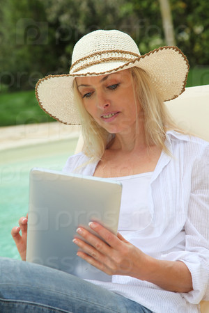 Woman resting in long chair with touchpad