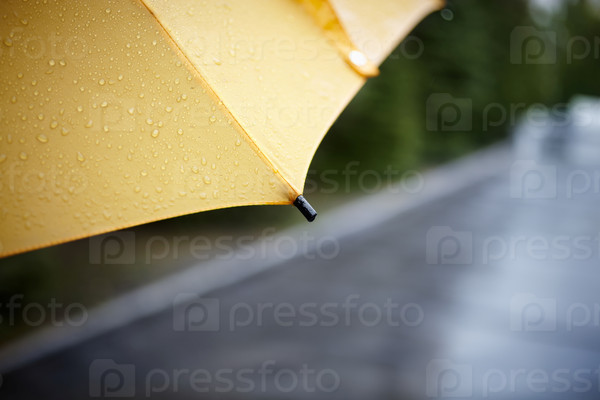 Дождей ходьбы с желтым зонтиком, выборочный фокус на ближайшей части