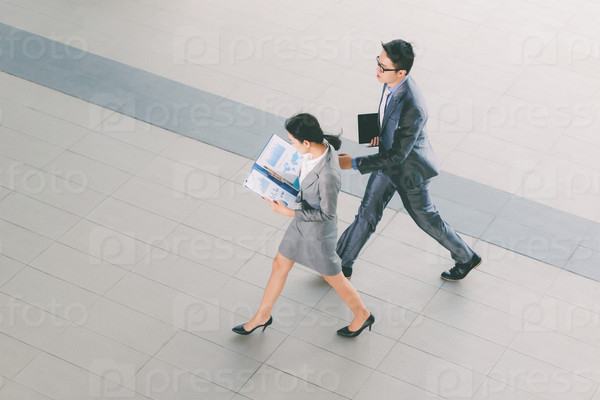 Young Asian business people with documents hurrying to work