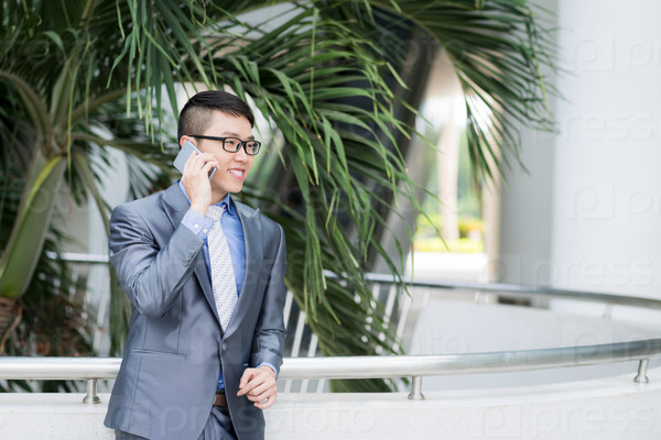 Portrait of cheerful Asian businessman calling on the phone