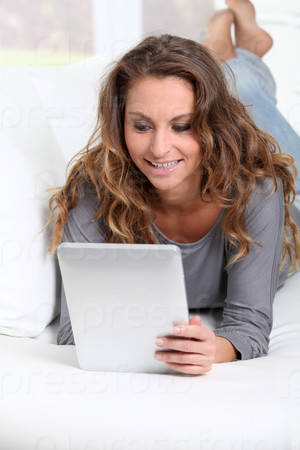 Beautiful woman laying on sofa with electronic tablet